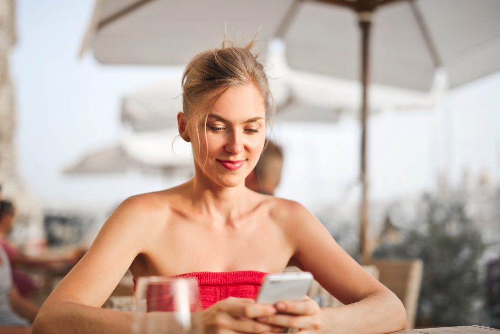 Woman looking at her phone on a restaurant patio