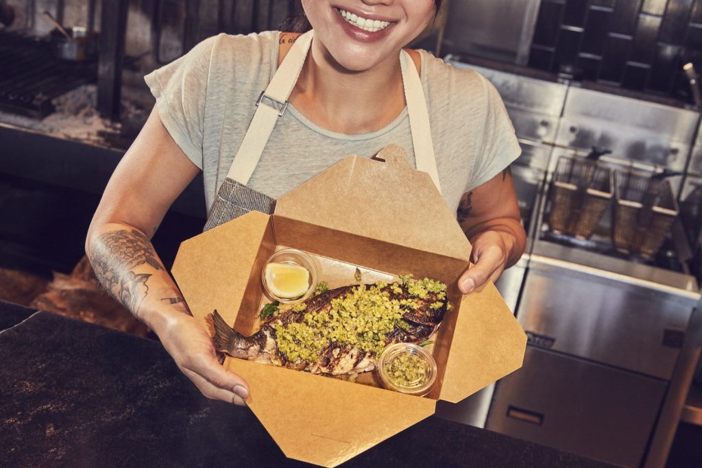 Chef holding up to-go box of fish